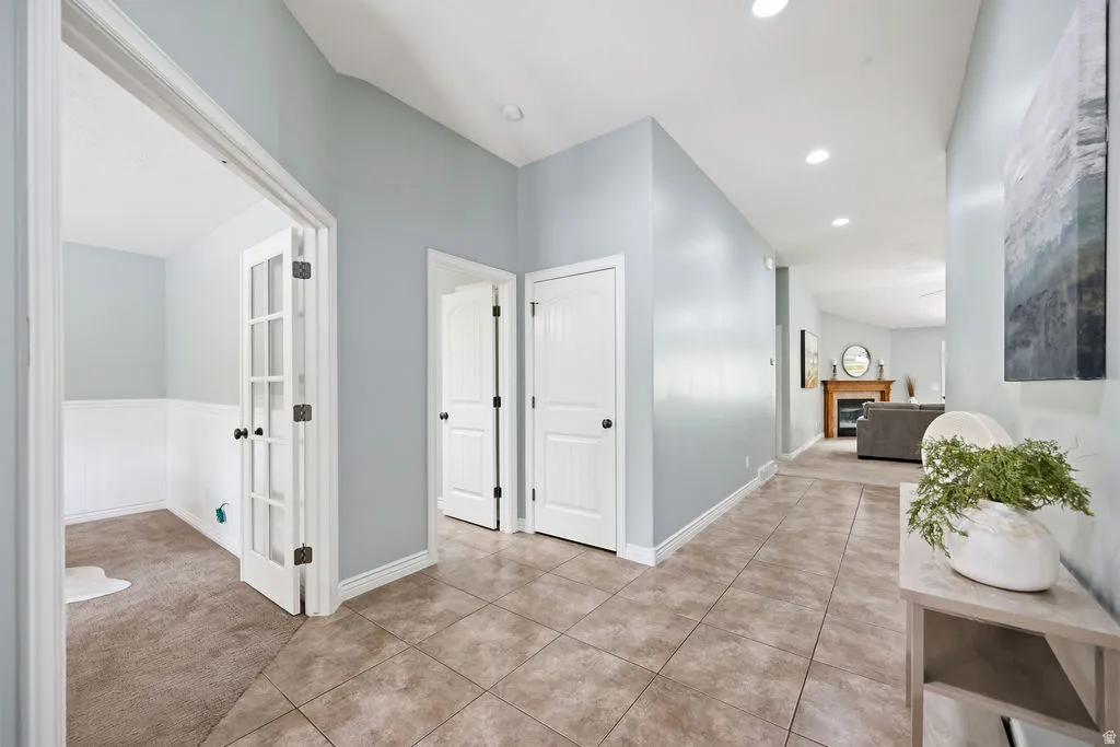 Entryway featuring large format tile flooring, a dedicated room with French doors, recessed lighting, and a view into a living area with a fireplace