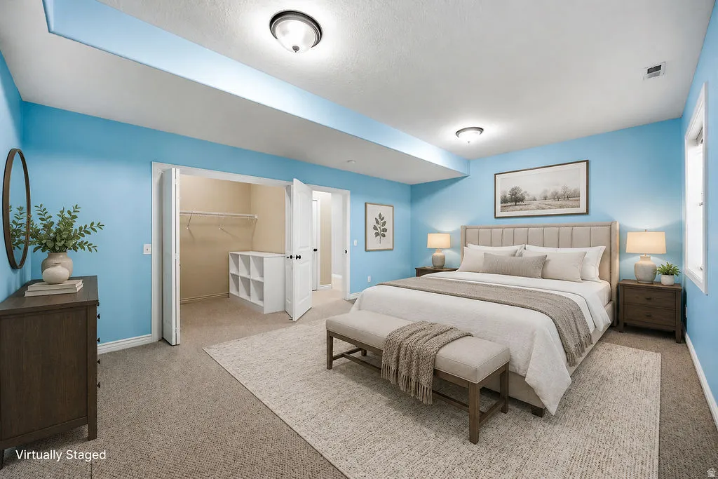 Spacious bedroom featuring light blue walls, gray carpeting, and a built-in closet system with shelving and hanging rods