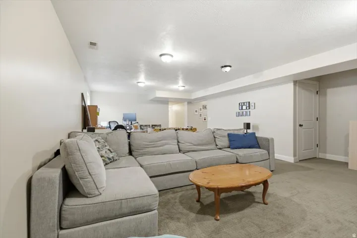 Lower level living area featuring light-colored walls, recessed ceiling lighting, a light-colored door with dark hardware, and carpet flooring