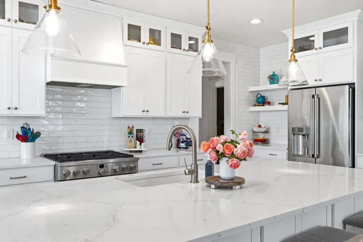 White shaker cabinetry with glass-front accents, stainless steel appliances, a gas range, and a white subway tile backsplash