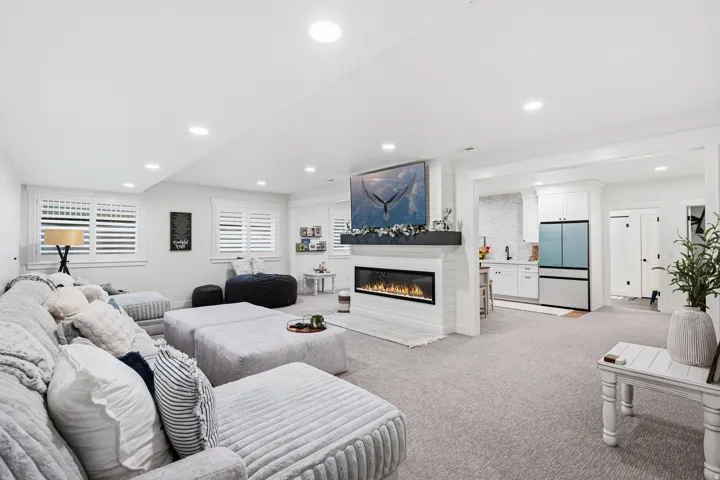 Spacious living area featuring an electric fireplace with a white shiplap surround, recessed lighting, and light-colored carpeting