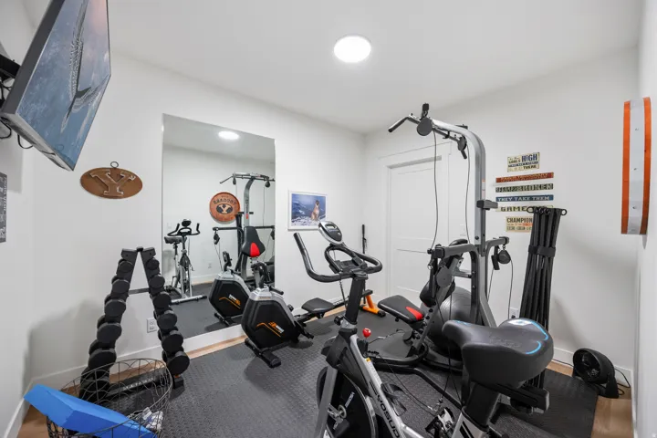 Dedicated fitness space featuring rubberized flooring, a full-wall mirror, and ample recessed lighting