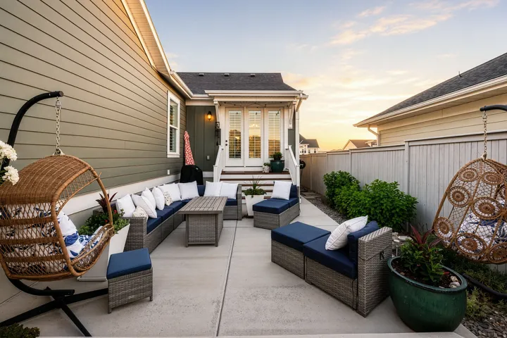 Concrete patio featuring a privacy fence, exterior lighting, and green siding