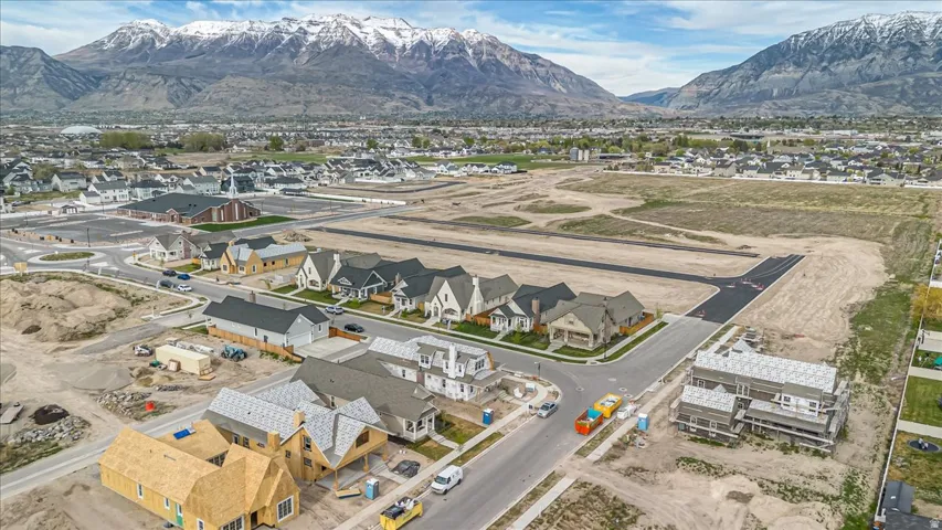 Residential development featuring new construction homes with varied architectural styles, paved streets, and mountainous terrain in the background