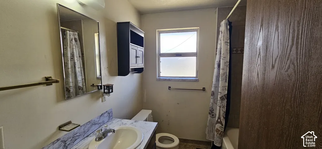 Bathroom featuring a vanity with a white basin and patterned countertop, a wall-mounted medicine cabinet, and a window for natural illumination