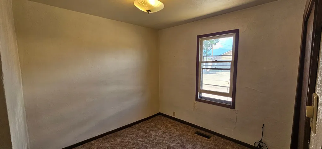 Neutral wall finishes with a single window featuring dark trim