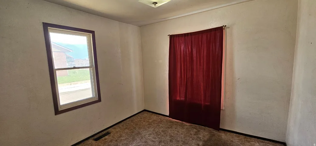 Room featuring carpet flooring, white walls, a single-pane window with wood trim, and an overhead light fixture