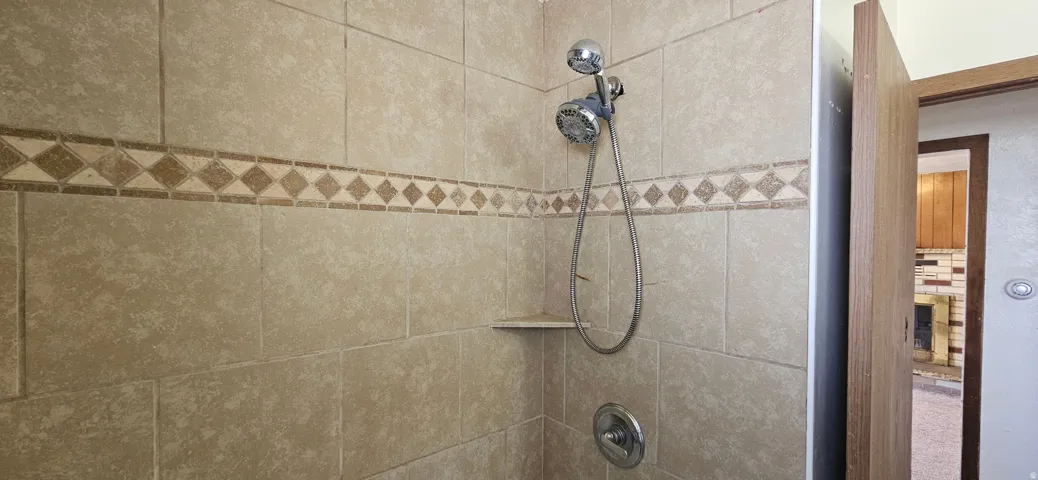 Tiled shower enclosure featuring a decorative mosaic accent band