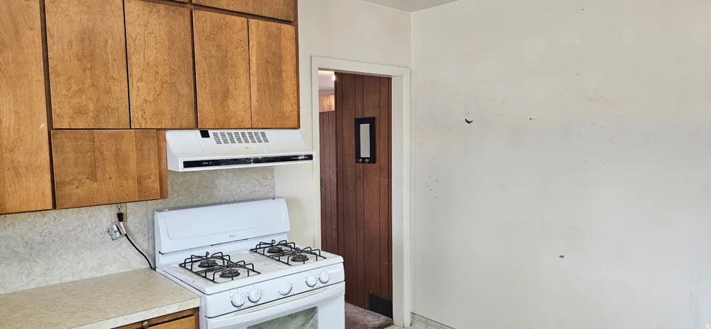 Main Home, Kitchen area featuring a white gas range, a white range hood, and wood-finish cabinetry