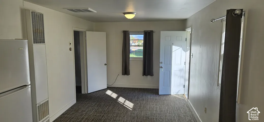 Interior room featuring wall-to-wall carpeting, a built-in wall furnace, dual-pane windows, and a flush-mount ceiling light fixture