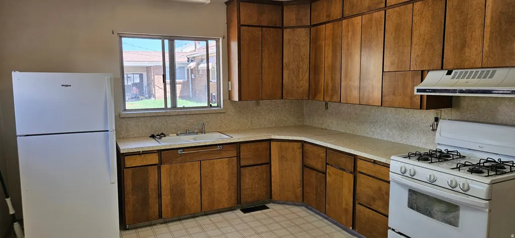 Kitchen featuring ample wood cabinetry, a built-in sink with a window above, white countertops, and checkerboard flooring