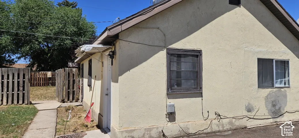Stucco exterior with multiple window openings, brown trim, and an asphalt shingle roof