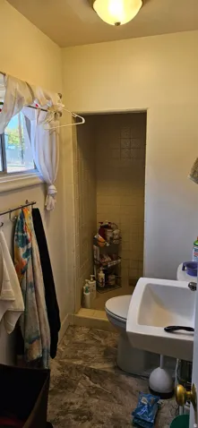 Bathroom featuring a tiled shower stall, white pedestal sink, and a window with natural light