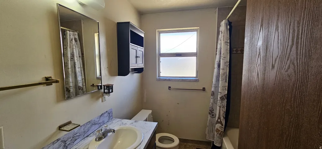 Bathroom featuring a vanity with a white basin and patterned countertop, a wall-mounted medicine cabinet, and a window for natural illumination