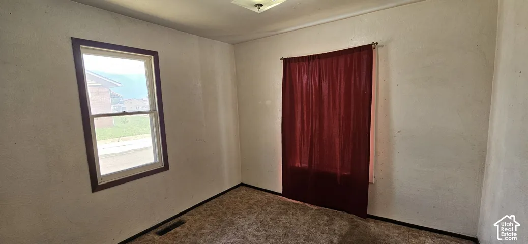 Room featuring carpet flooring, white walls, a single-pane window with wood trim, and an overhead light fixture