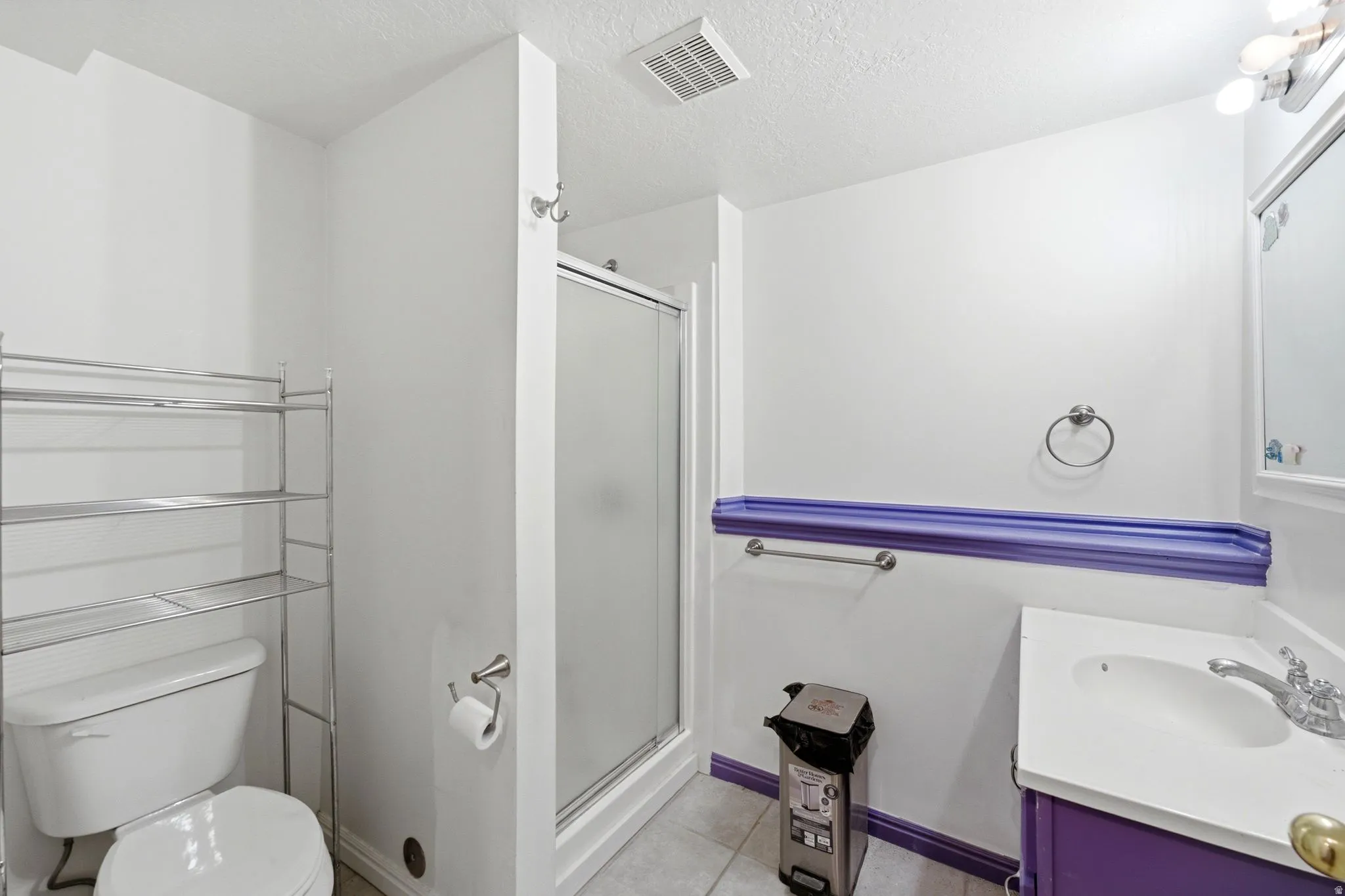 Bathroom featuring a glass-enclosed shower, single vanity with a white basin, and a toilet