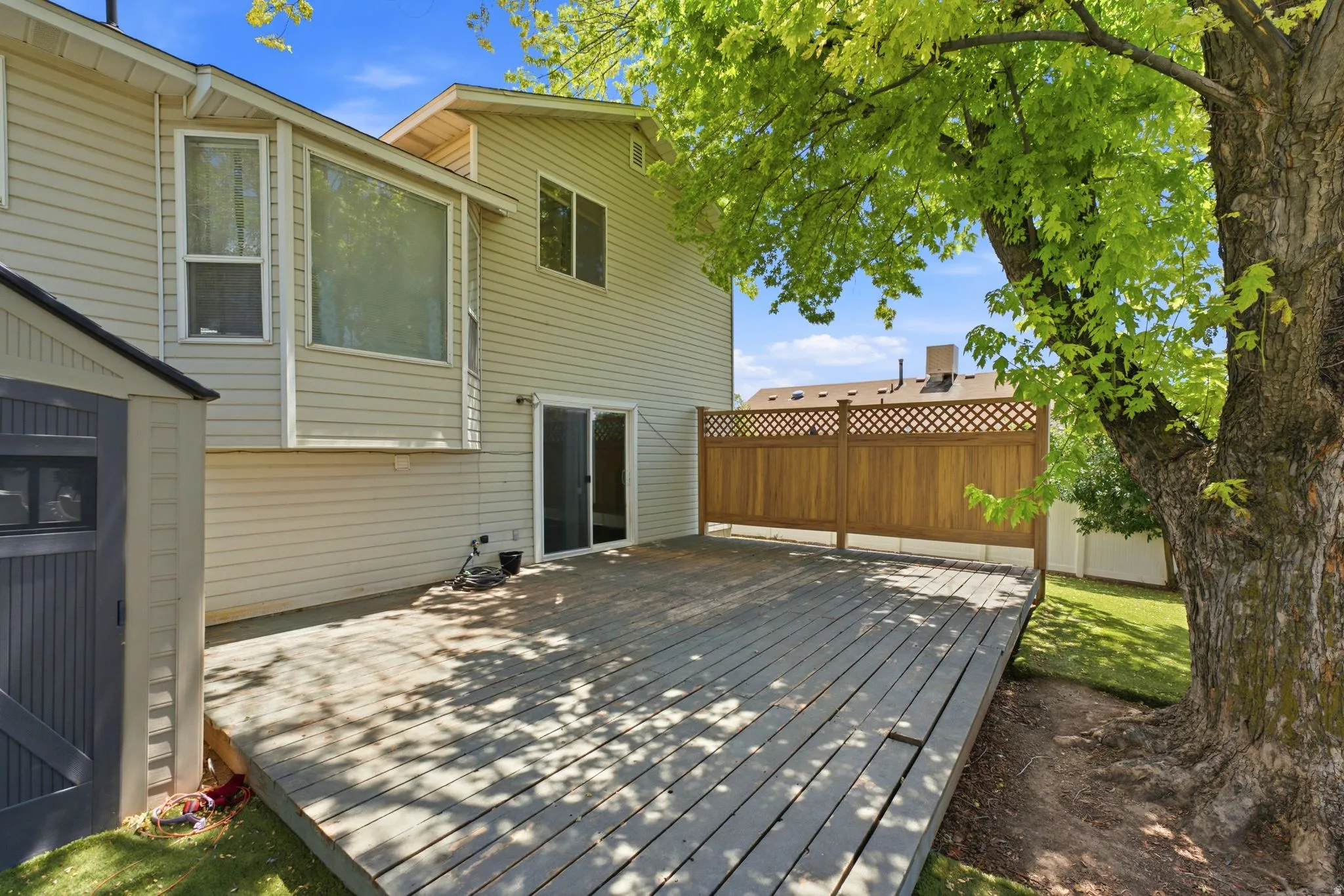 Spacious outdoor deck featuring wood flooring and a privacy lattice fence