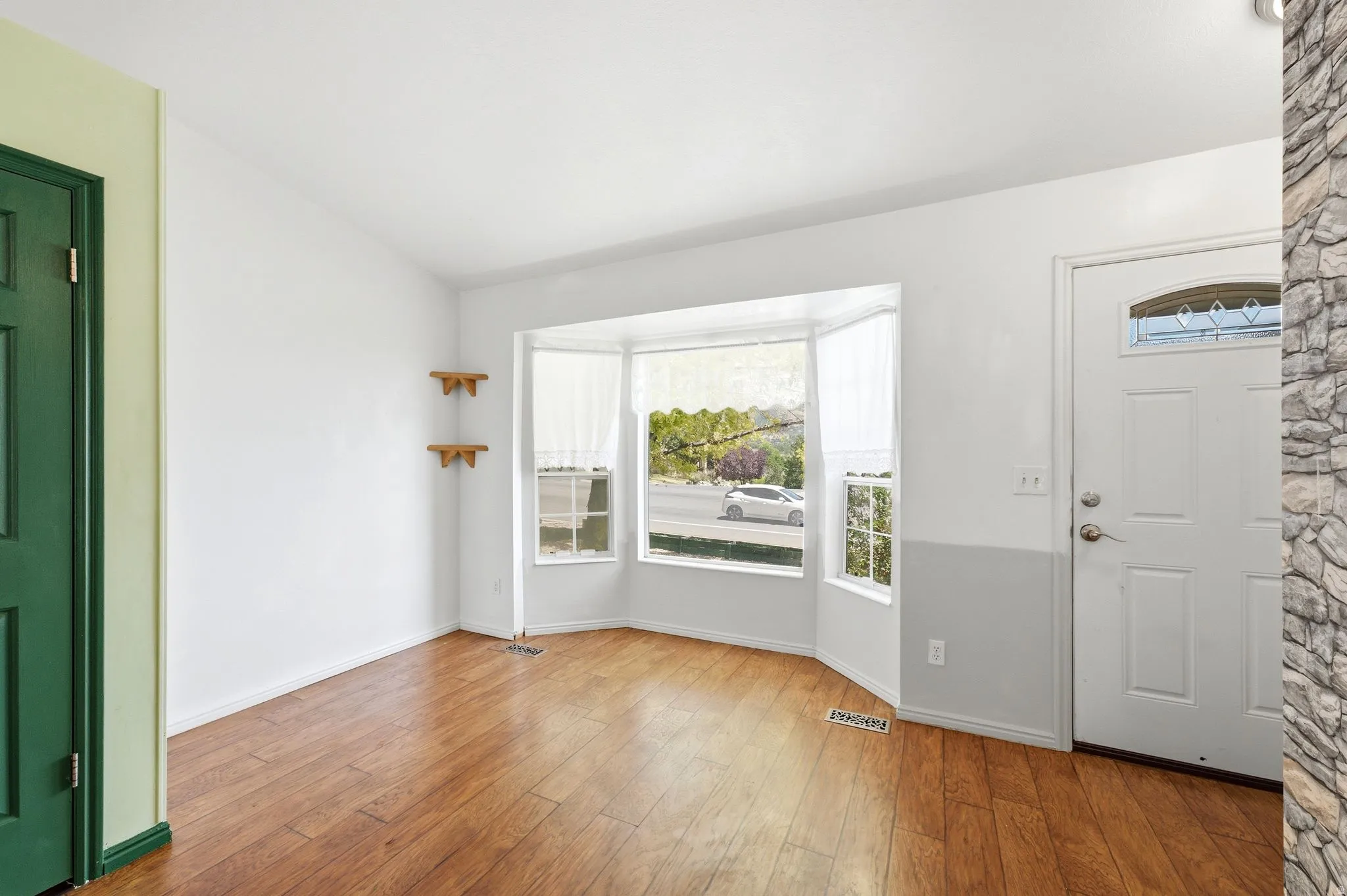 Bay window with white trim, wood-finish flooring, and white walls