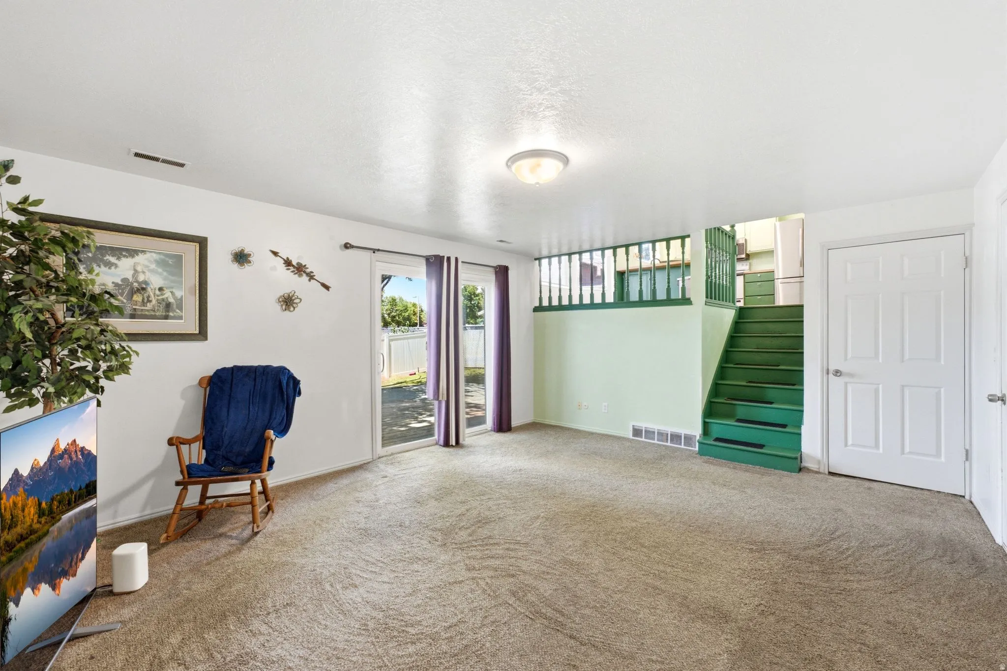Carpeted living area featuring white walls and a ceiling light fixture