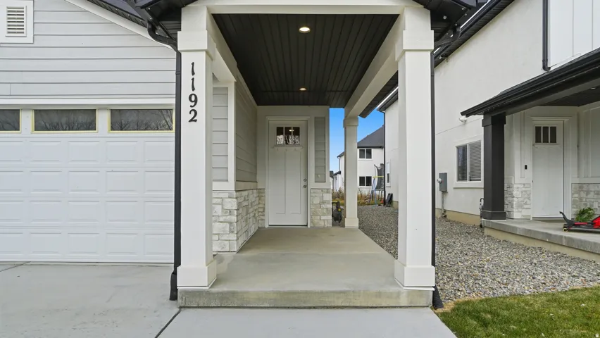 Covered entry with stone veneer accents and a paneled front door featuring upper window lites