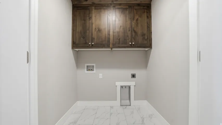 Dedicated utility space featuring elegant dark wood-finish cabinetry, light gray walls, white baseboards, and marble-look floor tiles