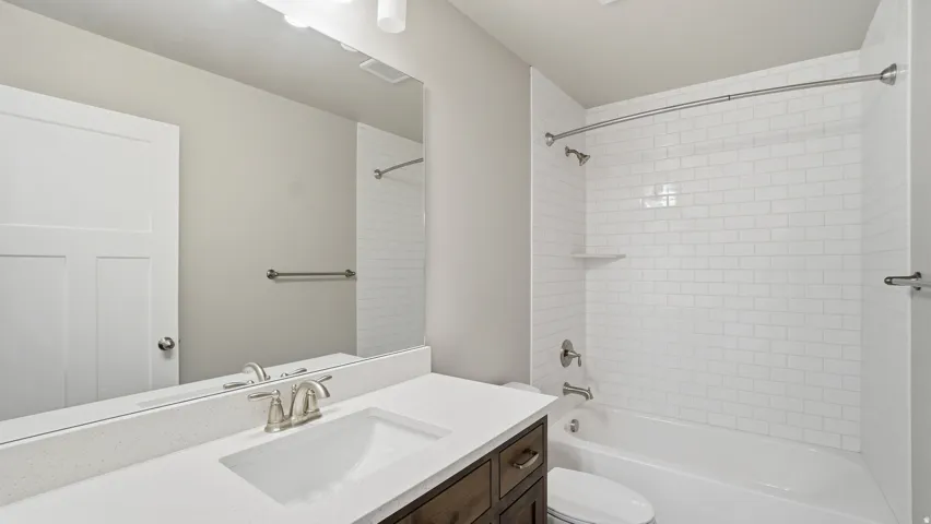 Bathroom featuring a dark wood-finish vanity with a white countertop and undermount sink, brushed nickel faucet, and a large wall-mounted mirror