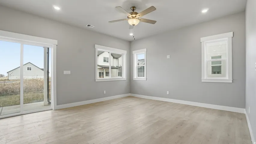 Spacious room with light wood-finish flooring, recessed lighting, and a ceiling fan