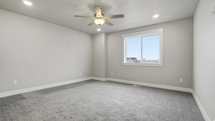 Spacious room featuring neutral grey walls and new grey carpeting