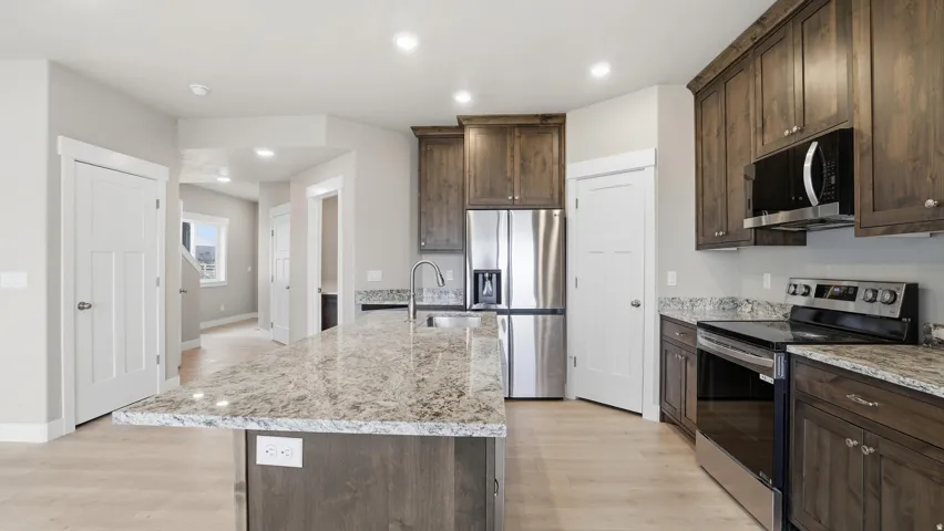Kitchen featuring wood-finish flooring, granite countertops, and dark wood cabinetry