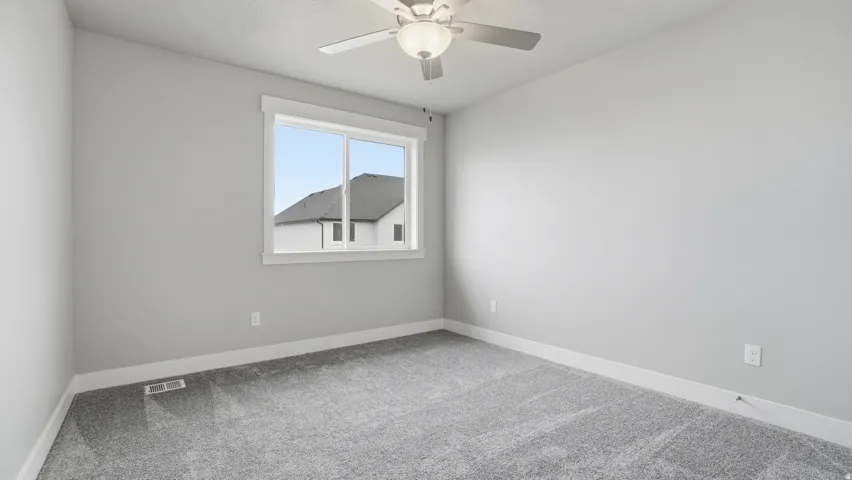 Bedroom featuring soft gray walls, neutral gray carpet, and a white-trimmed window