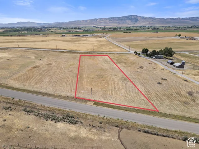 Expansive arid landscape nestled next to 2 vacant lots and a residential home.