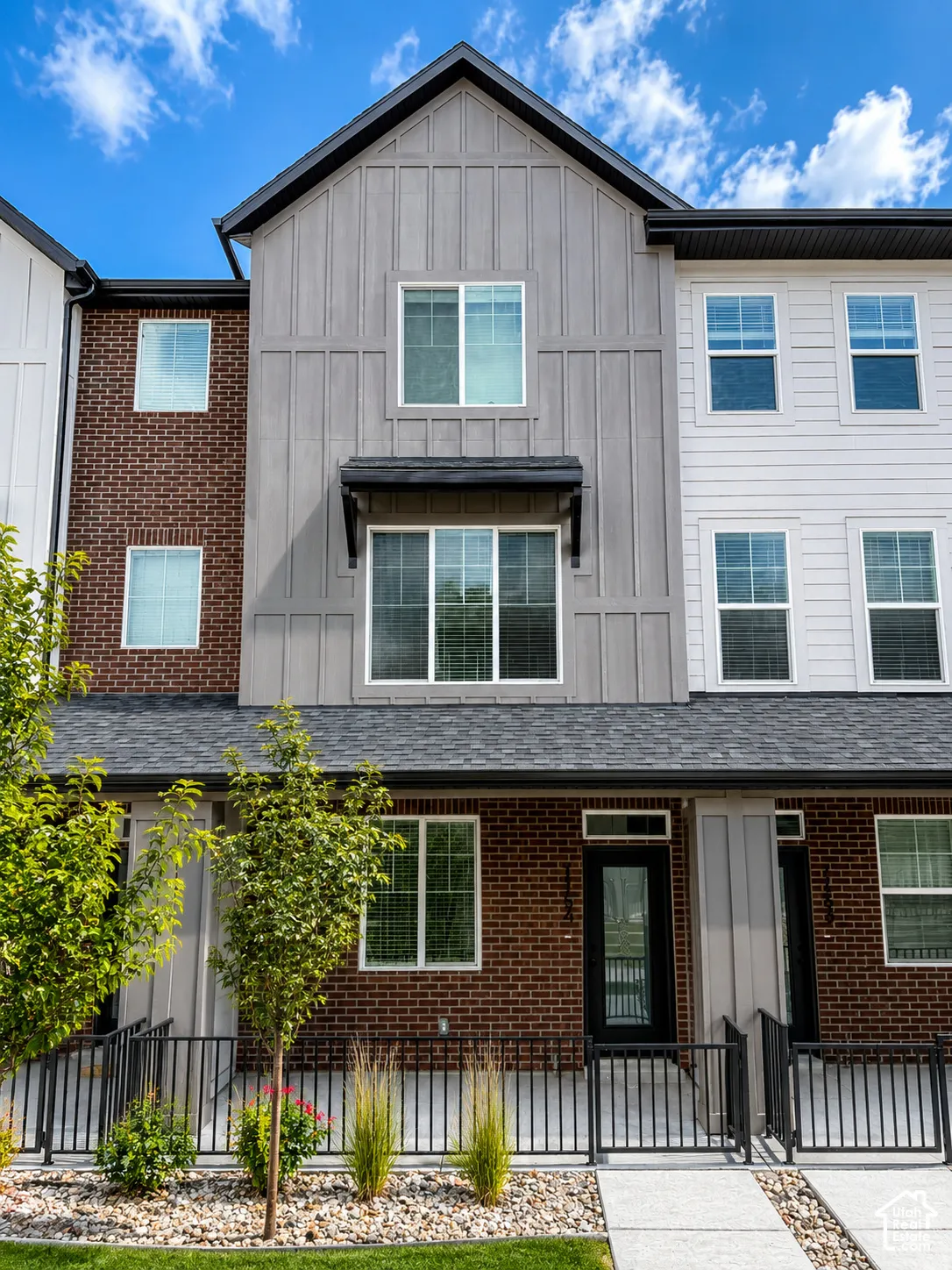 Modern townhome exterior featuring a combination of brick, vertical board-and-batten siding, and horizontal siding