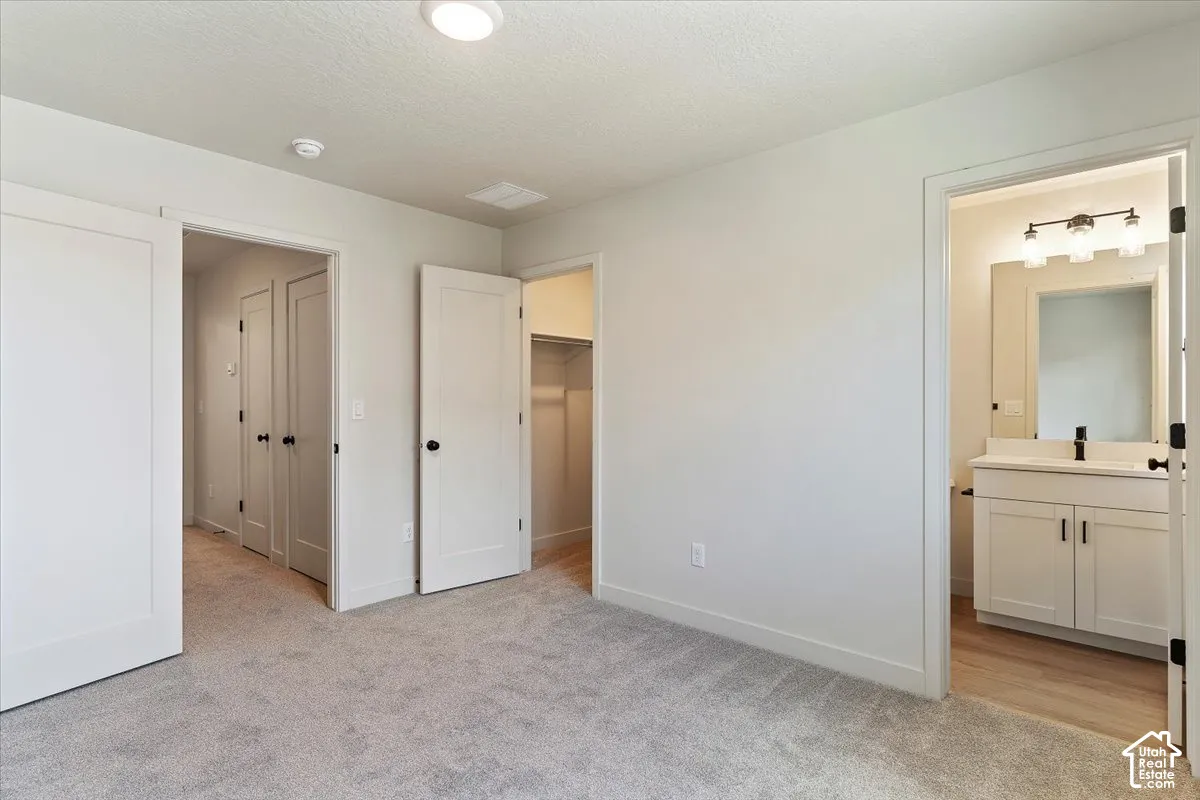 Spacious carpeted room featuring a ceiling-mounted light fixture, white trim, and doors with black hardware