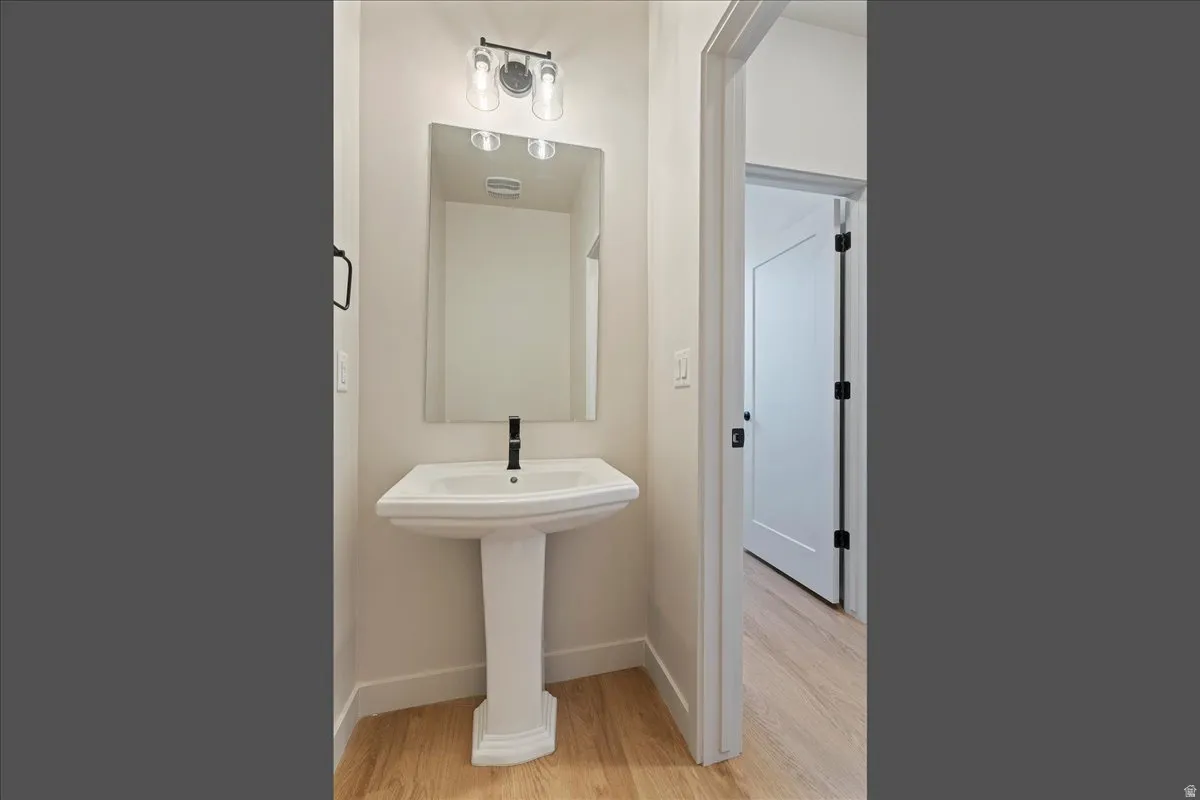 Pedestal sink with a black-finish faucet and rectangular mirror