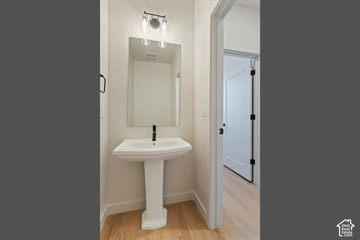 Pedestal sink with a black-finish faucet and rectangular mirror