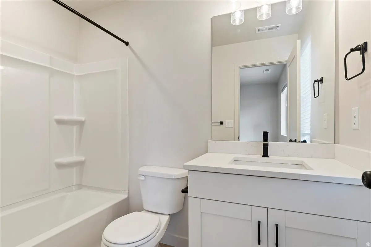 Bathroom featuring a white vanity with a light-colored countertop, an integrated rectangular sink, and a matte black faucet
