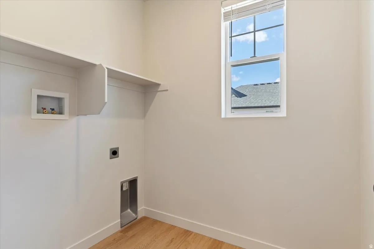 Laundry area with wood-finish flooring, built-in shelving, and a window for natural light