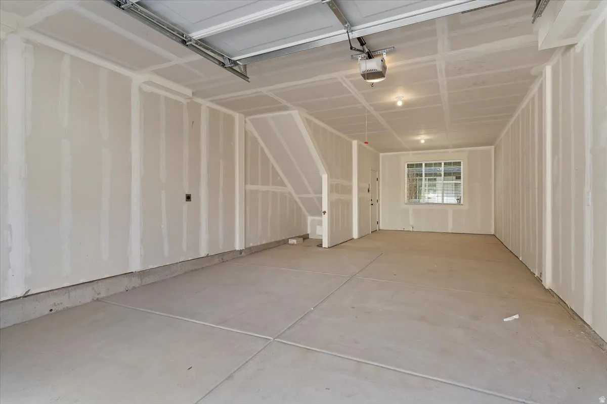 Spacious garage with unfinished drywall, concrete flooring, and an overhead garage door mechanism