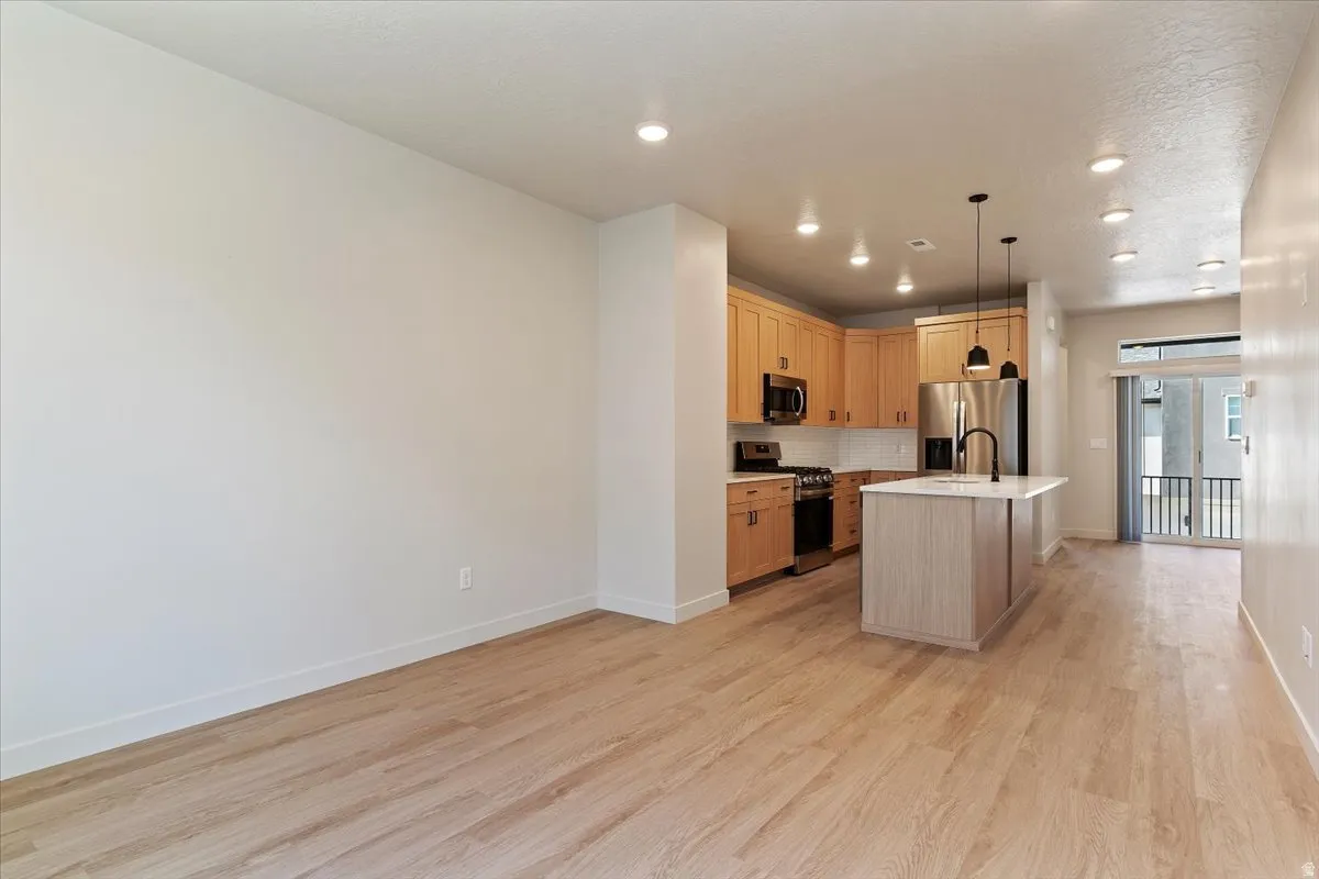 Open-concept living space featuring wood-finish flooring, recessed lighting, and a modern kitchen