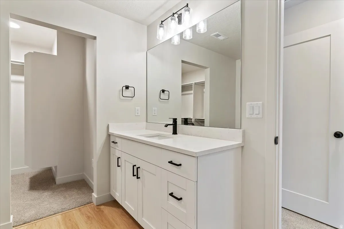 Bathroom vanity featuring a white shaker-style cabinet with matte black hardware, a white countertop, and a rectangular undermount sink with a matte black faucet