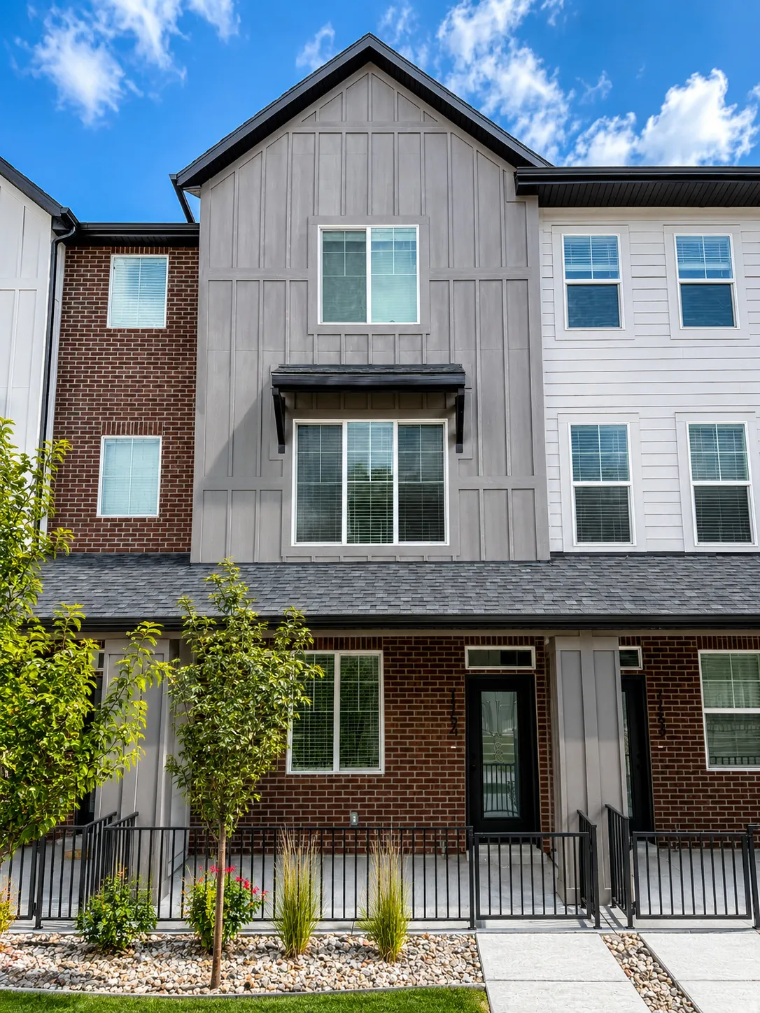 Modern townhome exterior featuring a combination of brick, vertical board-and-batten siding, and horizontal siding