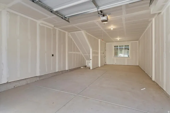 Spacious garage with unfinished drywall, concrete flooring, and an overhead garage door mechanism