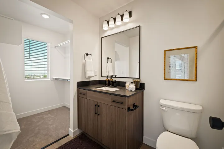Bathroom featuring a wood-finish vanity with a dark countertop, white undermount sink, and black hardware