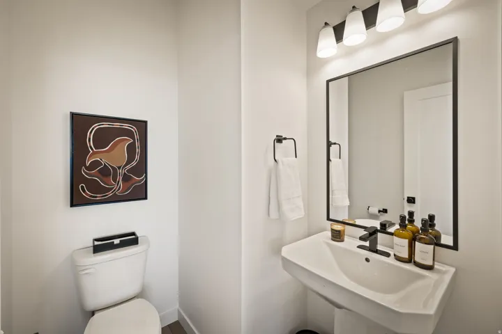 Modern bathroom featuring a pedestal sink, matte black faucet, and a rectangular mirror with a black frame