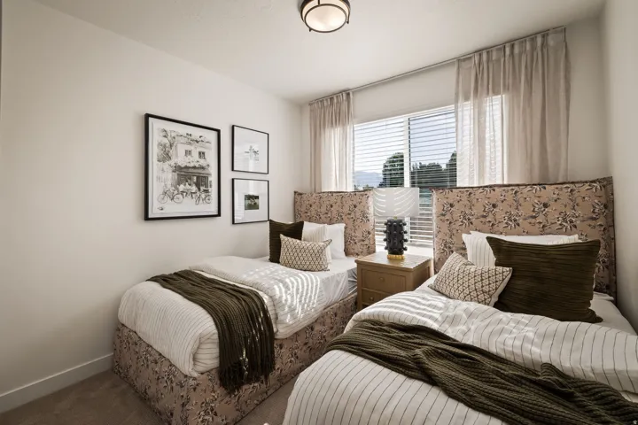 Bedroom featuring a large window with blinds and sheer drapes, framed artwork, and a built-in ceiling light fixture