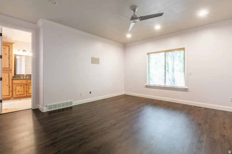 Spacious room featuring dark wood-finish flooring, white baseboards, and a modern ceiling fan with integrated lighting