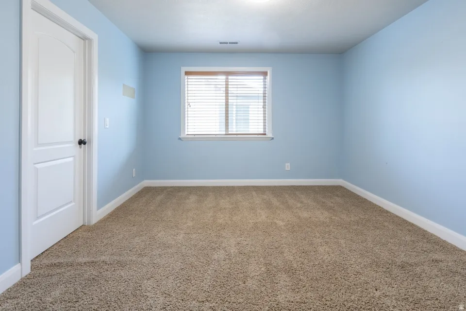 Inviting room with light blue walls and neutral-toned carpet flooring