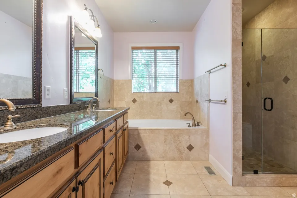 Bathroom featuring a dual vanity with granite-finish countertop, undermount sinks, and wood cabinetry