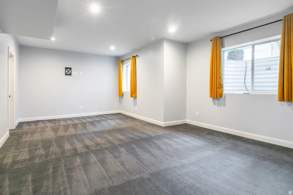 Spacious room featuring patterned carpeting, recessed lighting, and light gray walls