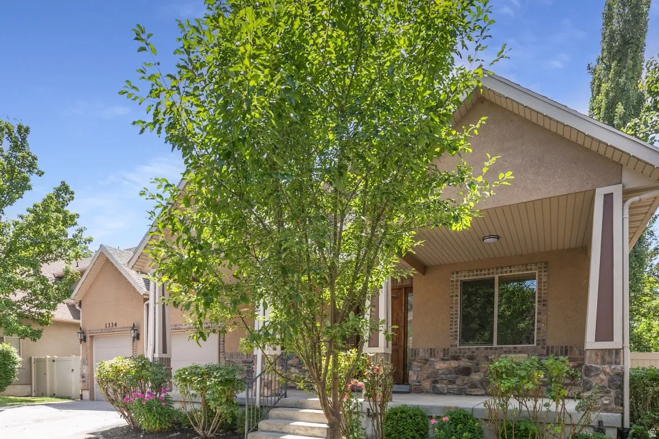 Stone and stucco exterior with a covered front porch featuring decorative columns